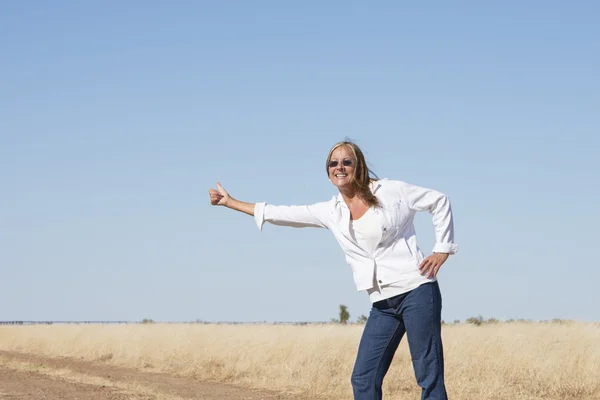Hitchhiking woman at country road — Stock Photo, Image