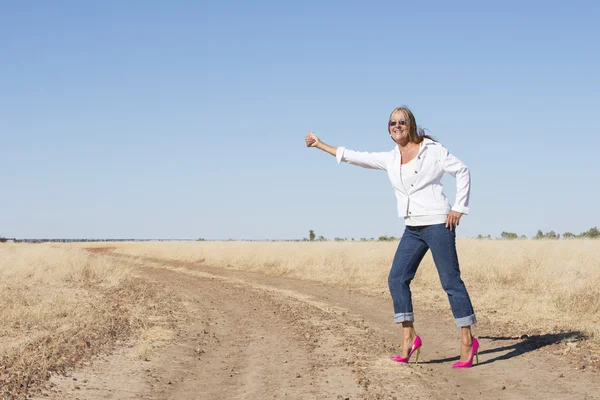 Woman in pink high heels hitchhiking in rural area — Stock Photo, Image