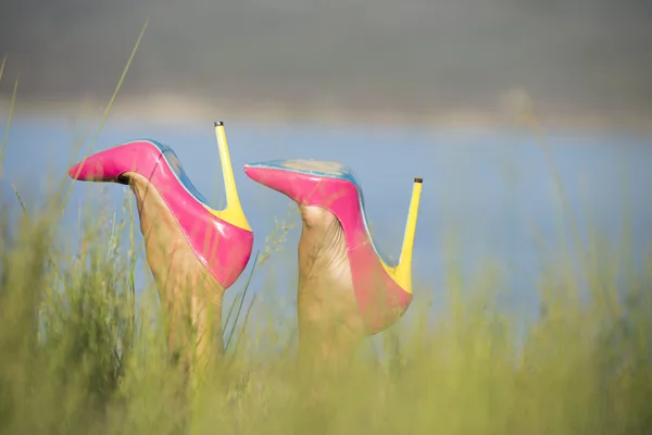 Peaking para fora sapatos de salto alto no campo de grama alta — Fotografia de Stock