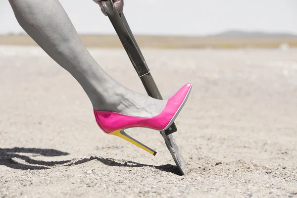 Pink high heel shovel digging in desert dirt — Stock Photo, Image