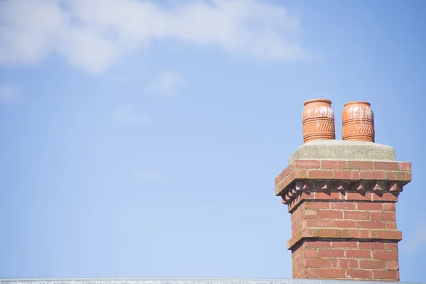 Cihlový komín na střeše s modrou oblohou — Stock fotografie