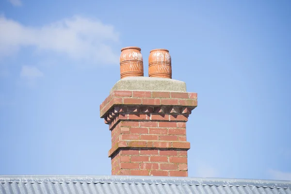 Red brick chimney on roof blue sky copy space Stock Picture