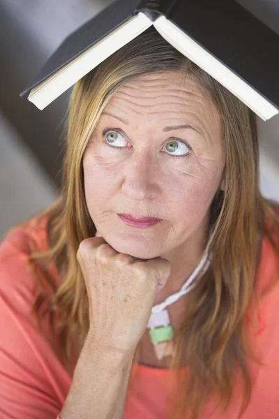 Portrait smart woman thinking with book on head