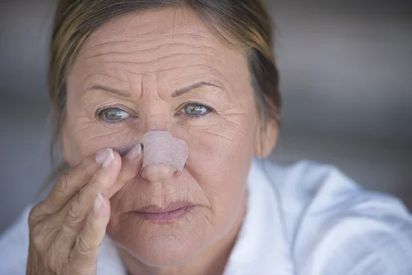 Ulykkelig kvinne med plaster på skadet nese – stockfoto