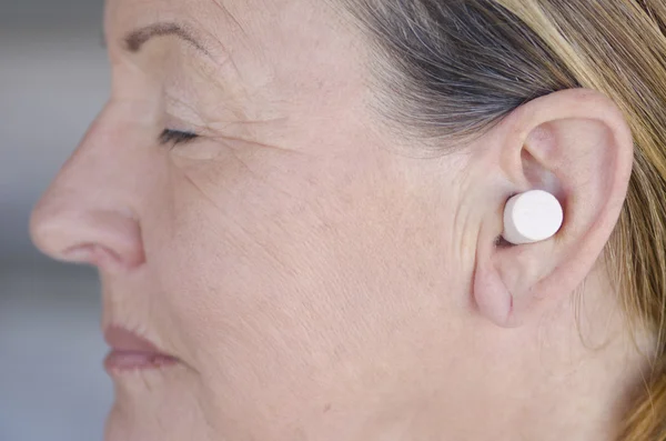 Жінка блокує звук з вушною пробкою закриті очі — стокове фото