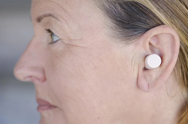 Woman blocking sound with ear plug — Stock Photo, Image