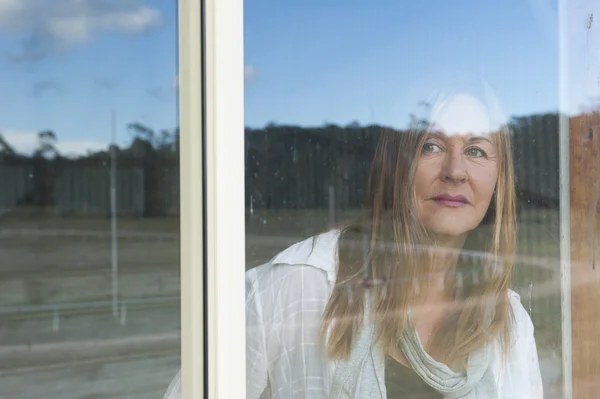 Mujer detrás de ventana observando al aire libre — Foto de Stock