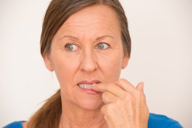 Nervous mature woman biting finger