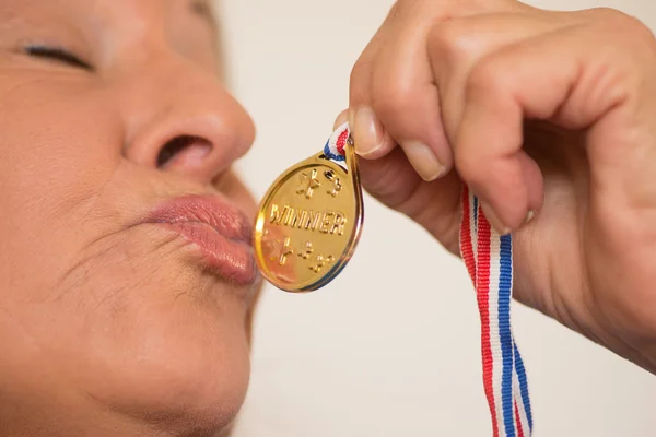 Mature woman kissing medal award — Stock fotografie