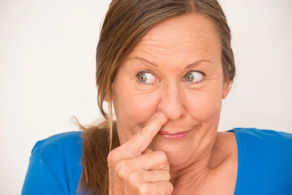 Funny mature woman blocking nose — Stock fotografie