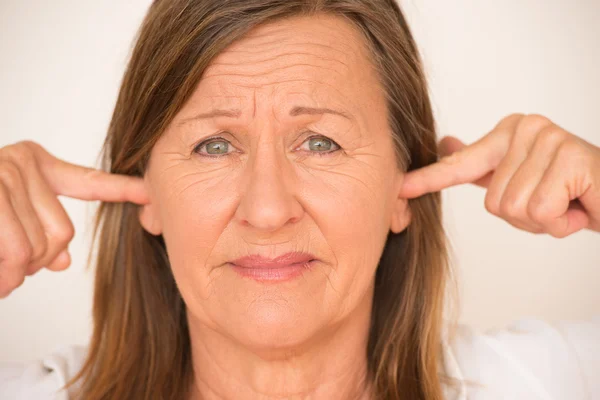 Woman blocking ears with finger — Stockfoto