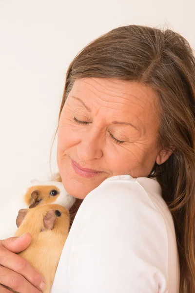 Mujer madura sosteniendo mascotas conejillo de indias — Foto de Stock