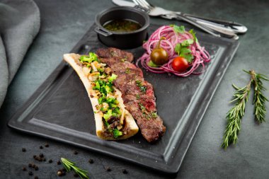 Kemikli biftek, soslu ve soğanlı salata, pomilor ve biberli. koyu arkaplan