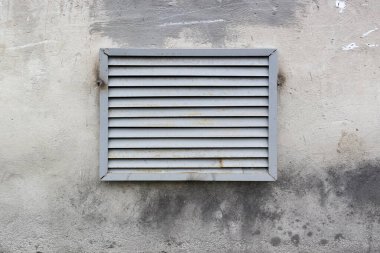 Paslı metal boyalı havalandırma ızgarası duvarda.