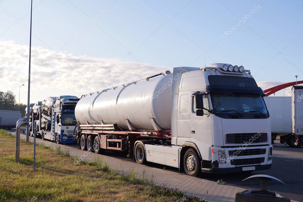 Trucks transporting various goods. Photo shows a tanker and a truck for transporting passenger cars. Road transport. 