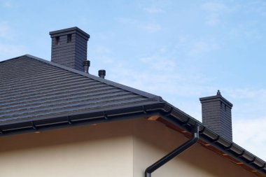 Yeni inşa edilmiş bir ev. Metal çatı kiremitlerinden yapılmış çatının bir parçası, yeni bacalar..