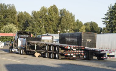 Standart dışı, alışılmadık yol ulaşımı. Ön planda, yarı römork taşıyan bir kamyon. Olağanüstü bir konvoy. Uzun araç. 