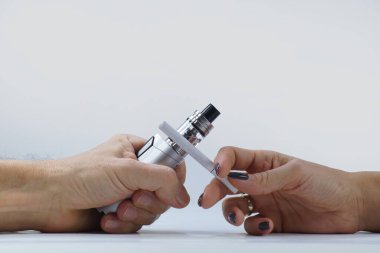 Bir kadın ve bir erkek eli. E-sigara ve normal bir sigara..