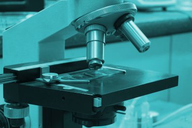 Laboratuvar odası bakteriyel ışıkla aydınlatılmış. Ön planda mikroskop.