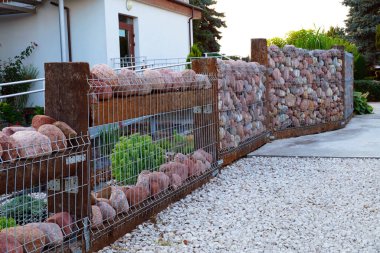 Çitleri çakıl taşlarından yapılmış bir ev. Gabion.