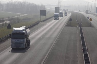 Ağır araç trafiği büyük miktarda egzoz gazı üretir. Otoyol sisle kaplı.. 