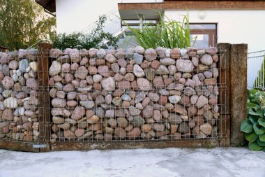 A specific form of a gabion made of pebble stones. Self-made fence made of stones.  clipart