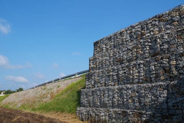 Strengthening the soil with gabions, stabilizing the embankment for the road.