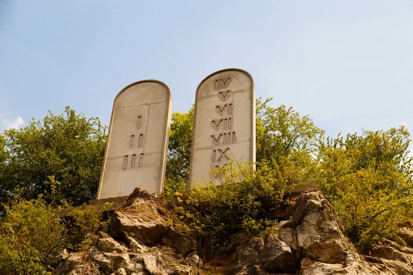 Stone tablets on a rocky hill with carved 10 commandments