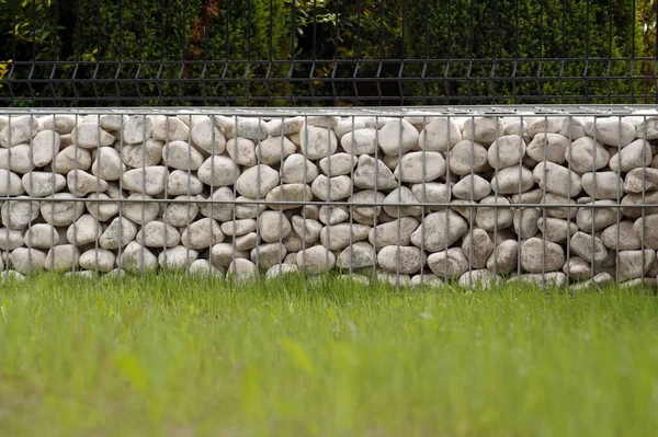 Impressive way of fencing the garden, metal baskets filled with white pebbles.