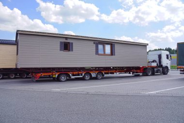 A very long and wide vehicle. Oversized cargo or exceptional convoy. A truck with a special semi-trailer for the transport of oversized cargo - transport of finished houses.