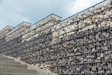 Eğim gabiyonlarla güçlendirildi. Gabion kullanımı ile park alanı ilginç bir düzenleme. 
