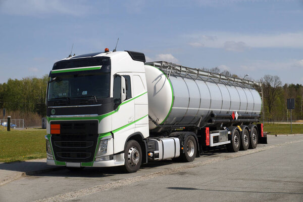 A truck during a break, a tanker in the foreground. Truck stop next to the highway.