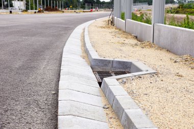 Yol yüzeyindeki fazla suyu kanalizasyon ızgarasıyla boşaltmak için beton modüllerden oluşan bir sistem. Otoyolun inşaatı. 