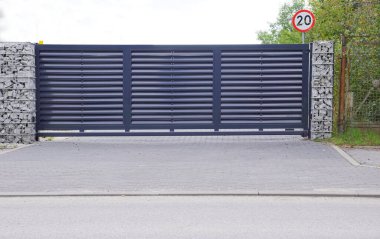 Gabiondan yapılmış bir duvarla kombinasyon halinde kullanılan otomatik giriş kapısı.