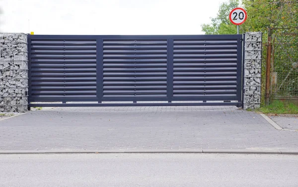  Gabiondan yapılmış bir duvarla kombinasyon halinde kullanılan otomatik giriş kapısı.