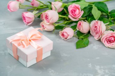 Hediye kutusu ve gri arka planda güzel bir buket pembe gül.