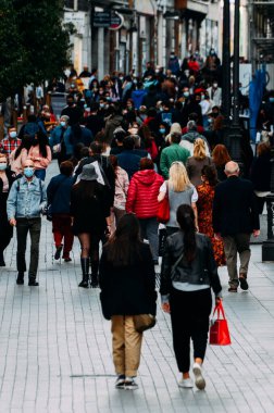 Madrid, İspanya - 01 Kasım 2020 Madrid, İspanya 'da kalabalık yaya caddesi. Covid-19 salgını sırasında insanlar zorunlu yüz maskesi takıyor. 300mm 'de yakalandı. Bokeh seçici odak