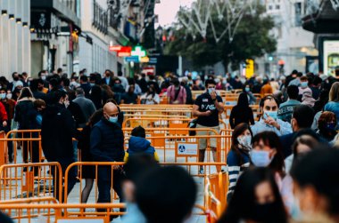 Madrid, İspanya - 01 Kasım 2020 Madrid, İspanya 'da kalabalık yaya caddesi. Covid-19 salgını sırasında insanlar zorunlu yüz maskesi takıyor. 300mm 'de yakalandı. Bokeh seçici odak