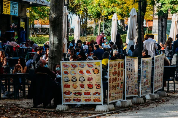 La gente se sienta en un patio con terraza en el Parque El Retiro en otoño, Madrid, España — Foto de Stock