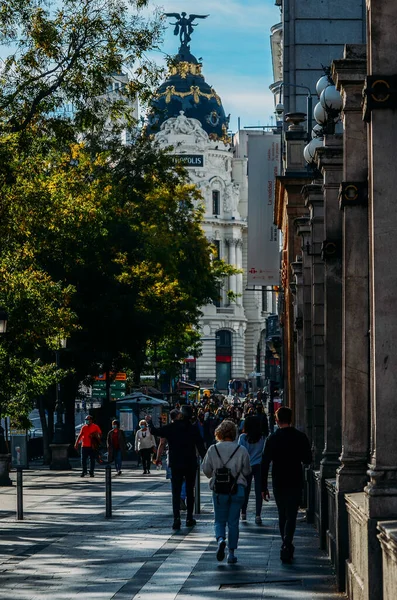 顔を覆う姿の人々が、グラン・ビア通りのエディフィオ・メトロポリスビルの近くを歩く。 — ストック写真