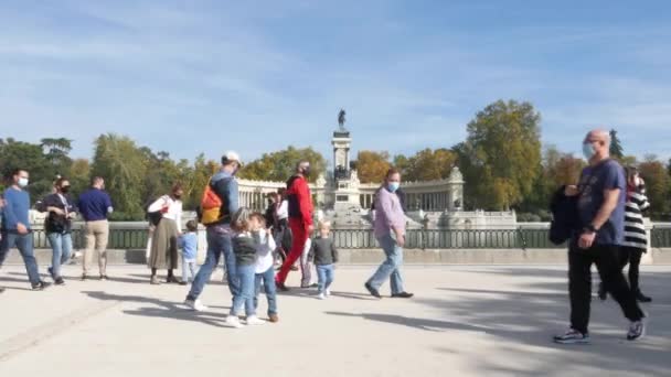 Pessoas vestindo coberturas de rosto passeiam ao lado do lago em Retiro Park, Madri, Espanha — Vídeo de Stock