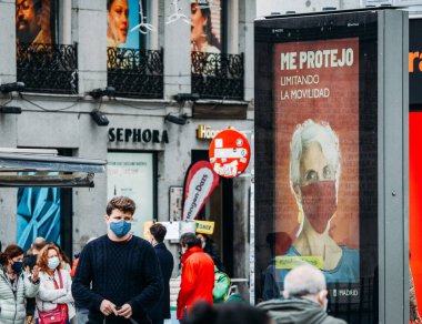 Madrid, İspanya - 15 Kasım 2020: Genç adam, Covid-19 salgını sırasında zorunlu yüz maskesi takıyor. Mesaj şu anlama geliyor: Hareket kabiliyetimi kısıtlayarak kendimi koruyorum.