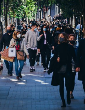 Madrid, İspanya - 21 Kasım 2020 Madrid, İspanya 'da kalabalık yaya caddesi. Covid-19 salgını sırasında insanlar zorunlu yüz maskesi takıyor. 300mm 'de yakalandı. Bokeh seçici odak