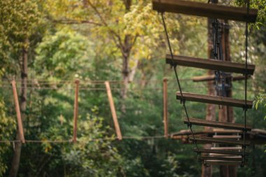 Tırmanan yapılar, platformları birbirine bağlayan tahta tahtalarla bir orman bölgesinde görülür. İpler ağaçların arasında asılı. Burası macera ve keşfe odaklı açık hava aktiviteleri için.