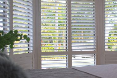 Luxury white indoor plantation shutters in bedroom - selective focus clipart