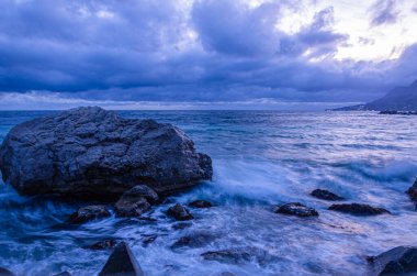 Akşam deniz manzarası. Kıyıdaki büyük taş.