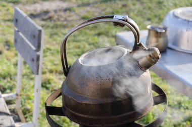 Bahçedeki metal bir çaydanlıkta su kaynıyor. Zor zamanlarda dışarıda yemek pişirmek. Gaz ve elektrik olmadan. Roket sobası.