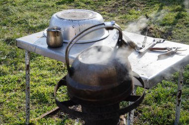 Bahçedeki metal bir çaydanlıkta su kaynıyor. Zor zamanlarda dışarıda yemek pişirmek. Gaz ve elektrik olmadan. Roket sobası.