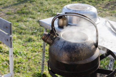 Bahçedeki metal bir çaydanlıkta su kaynıyor. Zor zamanlarda dışarıda yemek pişirmek. Gaz ve elektrik olmadan. Roket sobası.