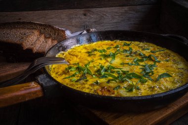 Fırında pişirilmiş dökme demir tavada patatesli kırsal omlet..